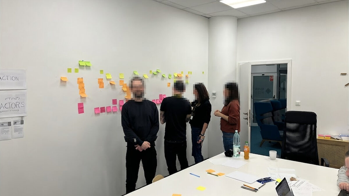 Participants standing at a wall of sticky notes during an AI opportunity mapping session, faces blurred